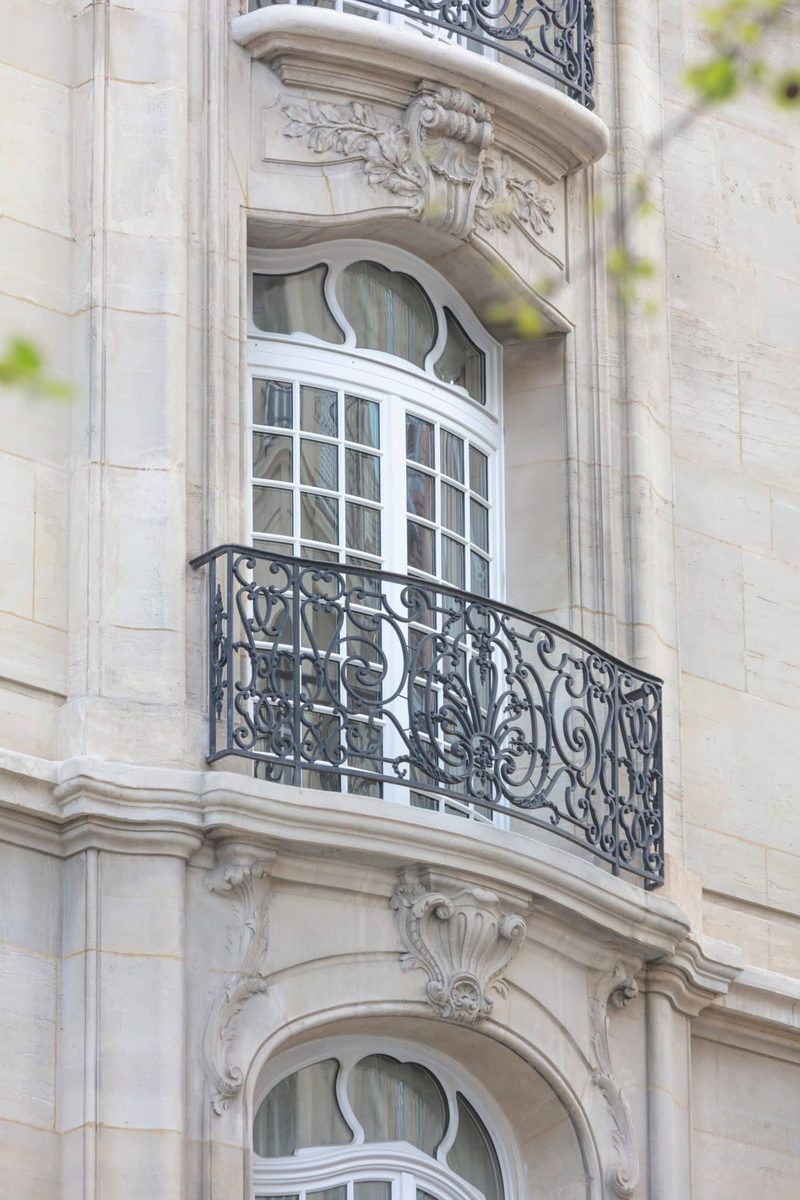 Fenêtre bombée à petits-bois sur façade en pierre sculptée