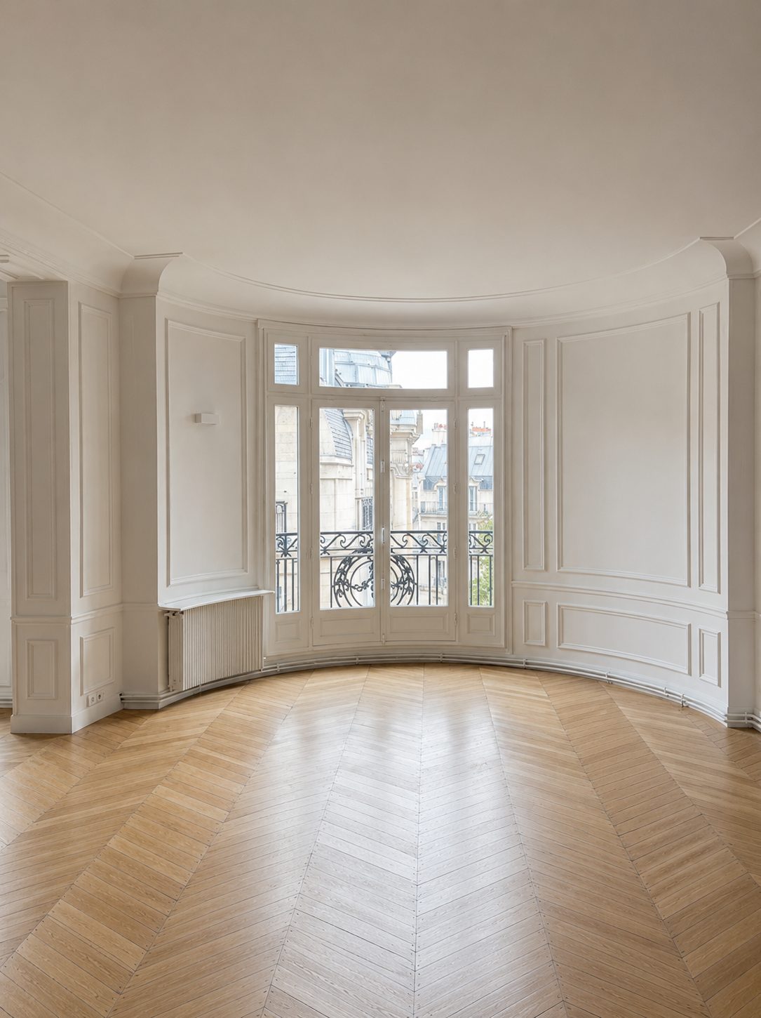 Baie cintrée vue de l'intérieur d'un appartement haussmannien au parquet en point de Hongrie